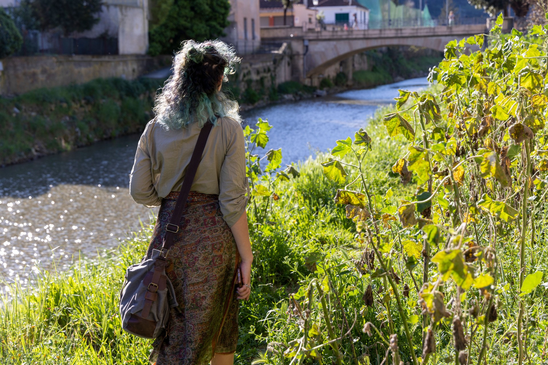 Young, mixed race, generation z woman walks along riverbank